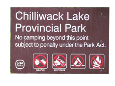 A brown provincial park sign for British Columbia Parks featuring a sun and water graphic.