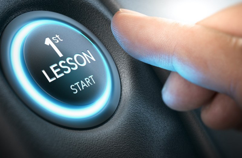 A close-up of a finger about to press a glowing blue circular button that reads "1st LESSON START."