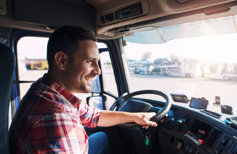 A man is smiling while driving a large truck.