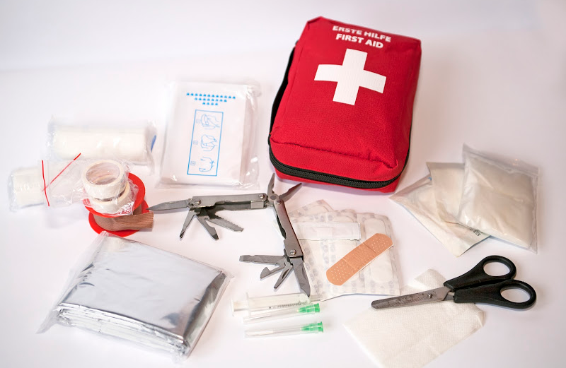 A compact motorcycle first aid kit bag unzipped to reveal various medical supplies, including bandages, gauze, and disinfectant.