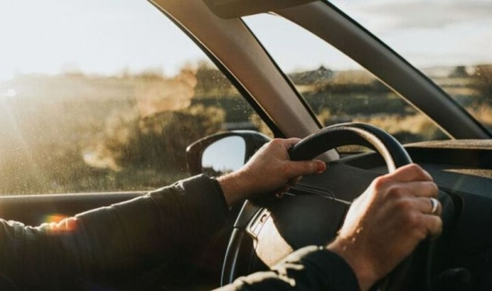 2 hands on the steering wheel of a car.