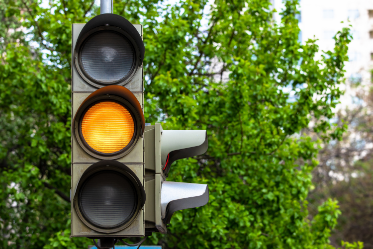 A close-up of a traffic light with the yellow light illuminated.