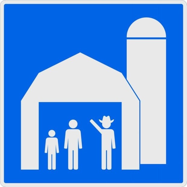 A blue and white sign featuring a barn, silo, and a person in a cowboy hat.
