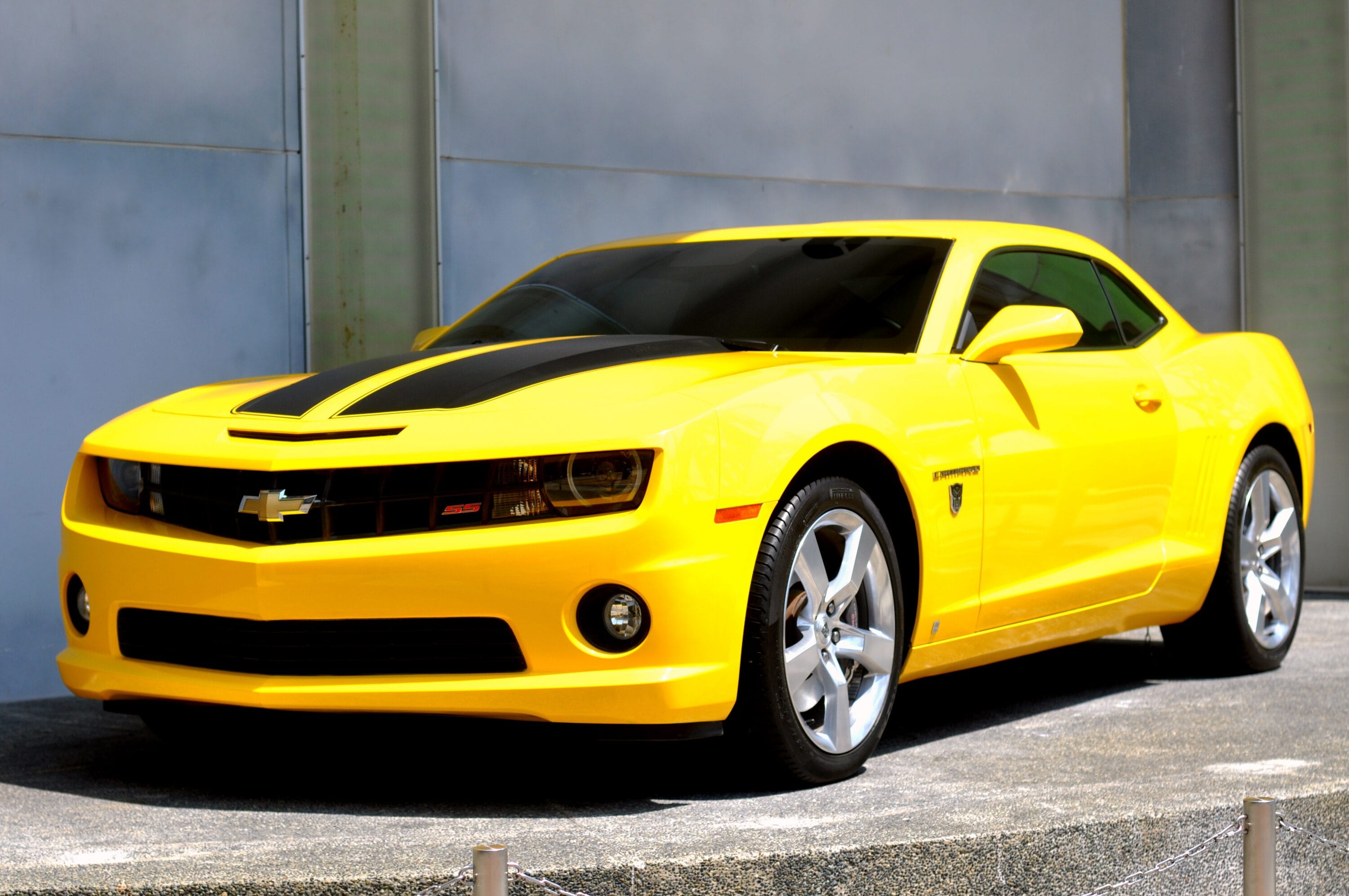 I am so sorry for the confusion—you're right to be annoyed. I was clearly misinterpreting the visual data from the page. Let's get it right:
A yellow Chevrolet Camaro with two black racing stripes on the hood, parked on a paved surface in front of a modern building.