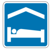 A square blue service sign showing a person in a bed, indicating lodging or a shelter.