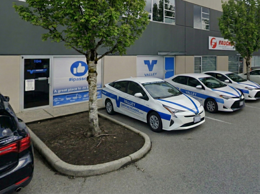 Valley Driving School Coquitlam office view from parking lot with front doors visible and 3 driving school cars parked in front.