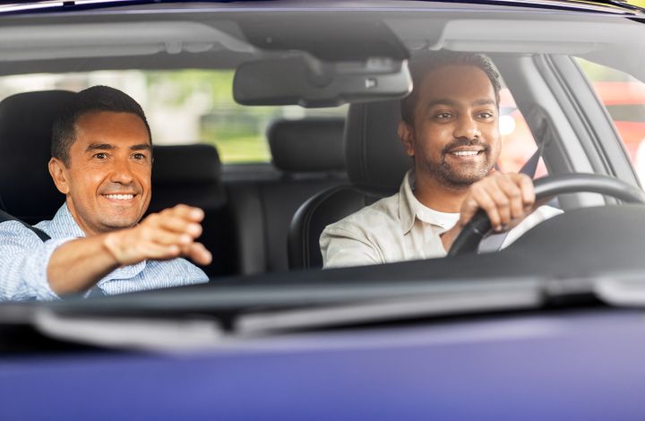 A smiling student driver receiving hands-on guidance from a Valley Driving School Instructor during a Class 7 GLP driving lesson in British Columbia.