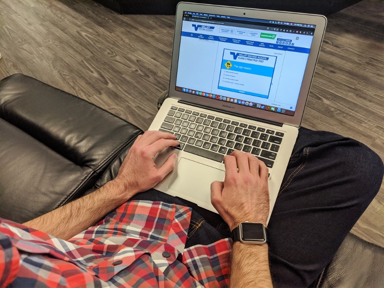 a man is sitting on a coach and using a laptop to answer test questions.