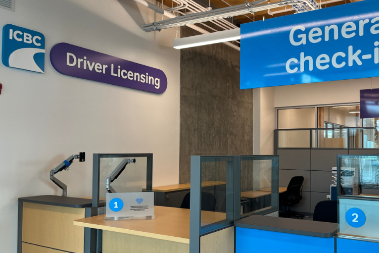 An interior view of an empty ICBC Driver Licensing service center, featuring numbered counters and signs for "Driver Licensing" and "General check-in".