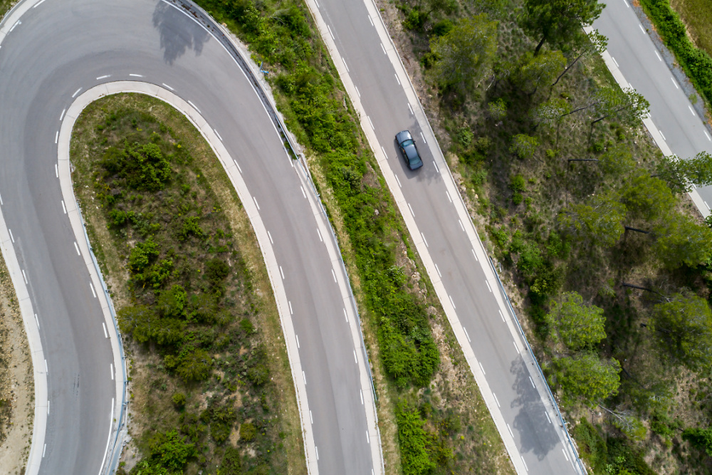 A Birds Eye view of a winding road with a car driving.