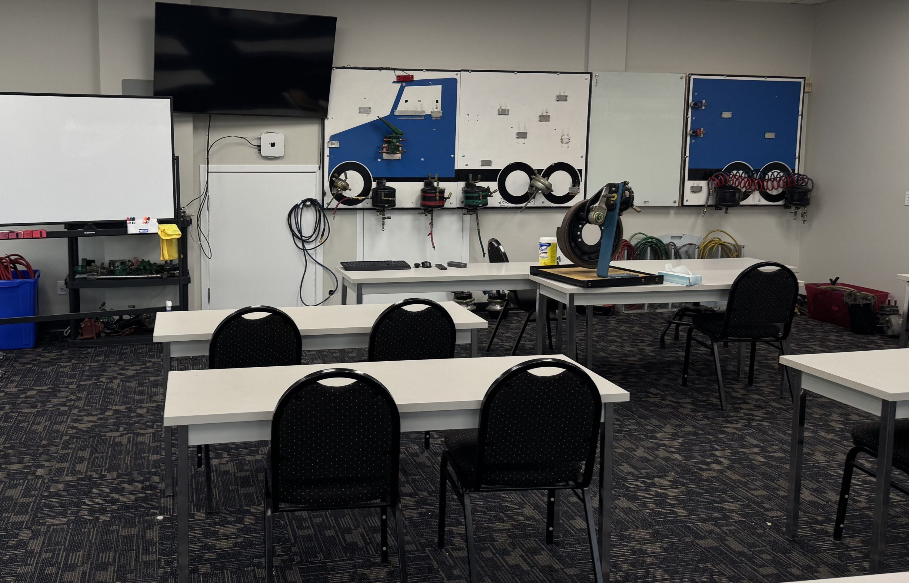 A Valley Driving School classroom in Chilliwack featuring desks, a whiteboard, and specialized instructional air brake boards on the walls.