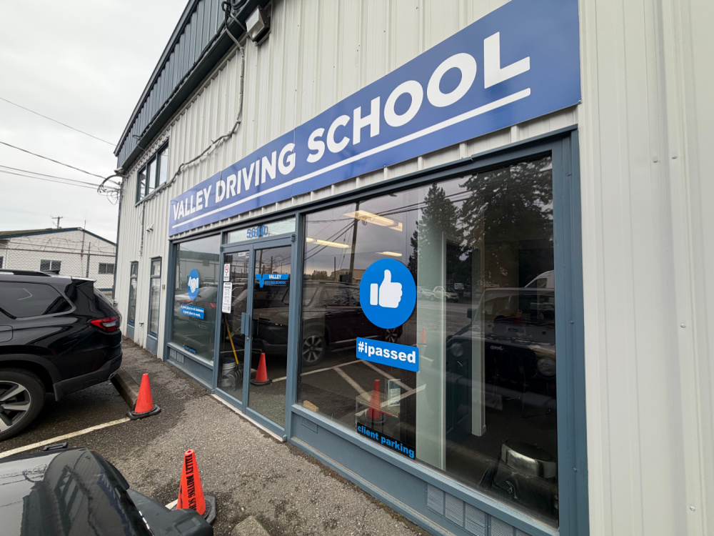A white and blue building with a sign above the front doors that says Valley Driving School