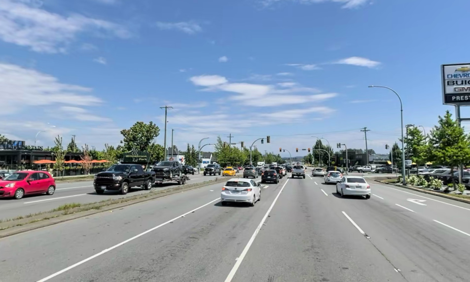 Multi lane roadway in Langley BC with cars travelling in either direction. Multiple cars are waiting to turn left and other cars waiting to go straight through at a red light.