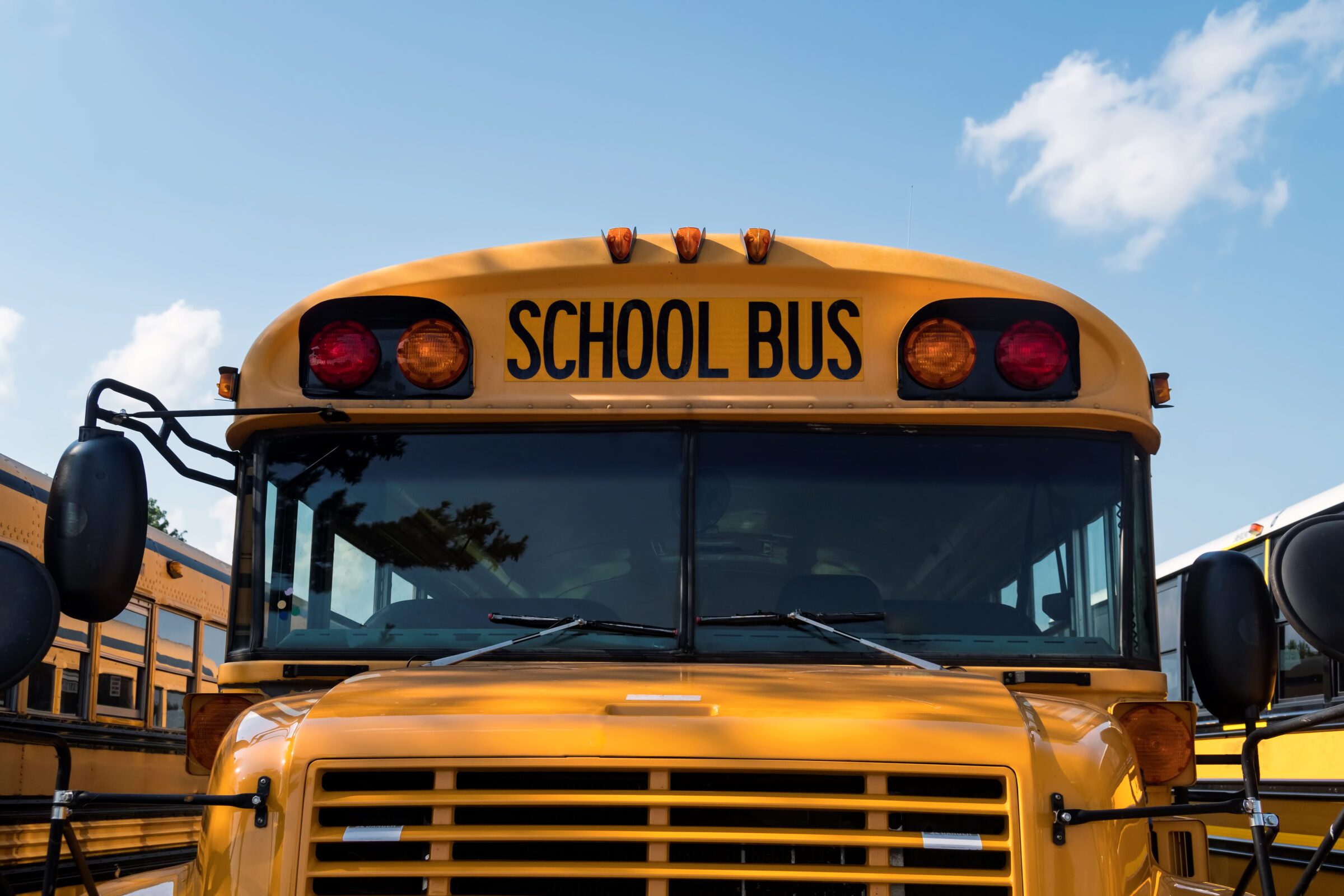 zoomed in view of yellow school bus grill, windshield and lights