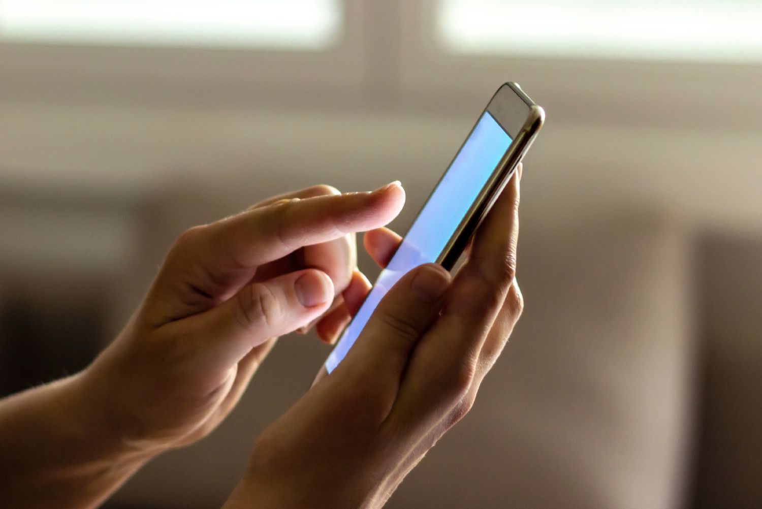 A person holding a smartphone and using their thumb to scroll through content on the screen.
