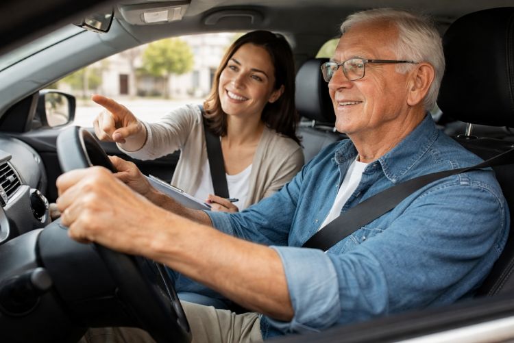 An interior view of a car with an older adult male driving while a passenger sits in the front seat next to him.