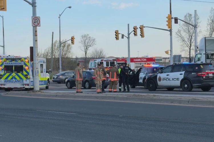 A police cruiser parked at a busy road intersection with its emergency lights flashing.
