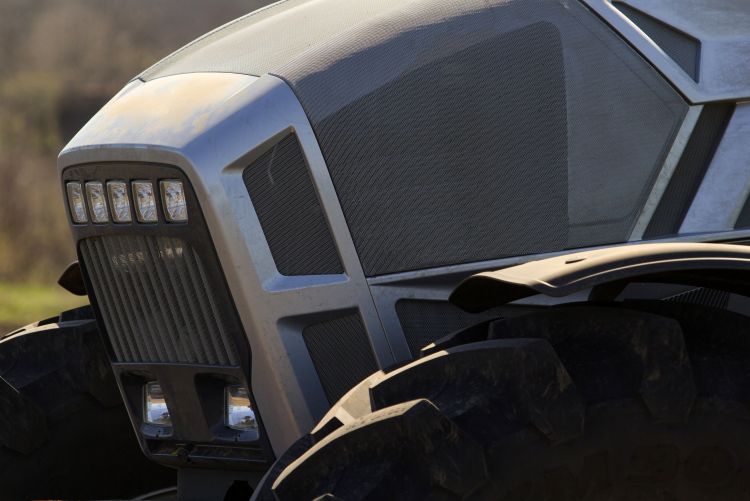 A close-up view looking up at the large, enclosed glass cab of a modern grey farm vehicle or tractor.