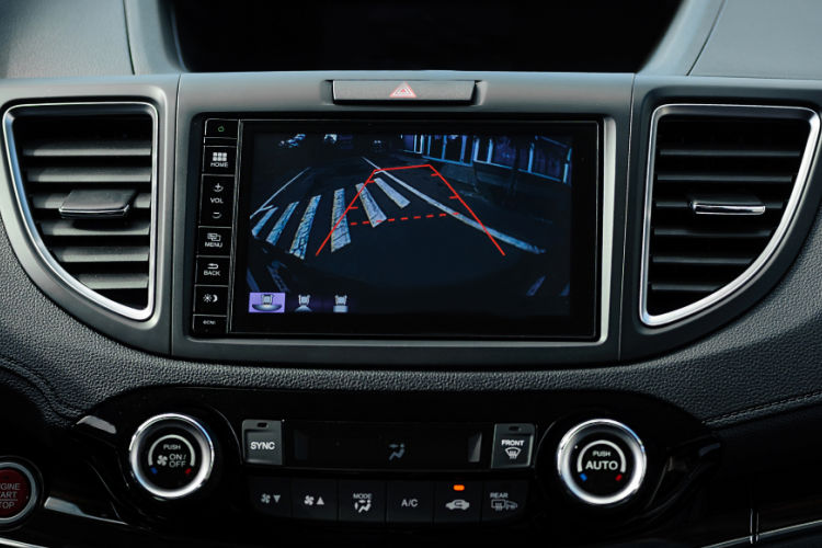 This image shows a close-up of a vehicle's dashboard backup camera display screen, illustrating the digital view behind the car with color-coded guidelines to assist with reverse parking.