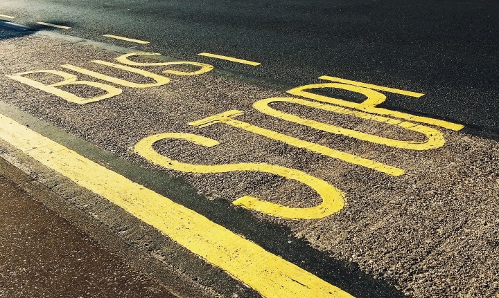 A view of the road with **"BUS STOP"** painted in large yellow letters on the asphalt road surface.