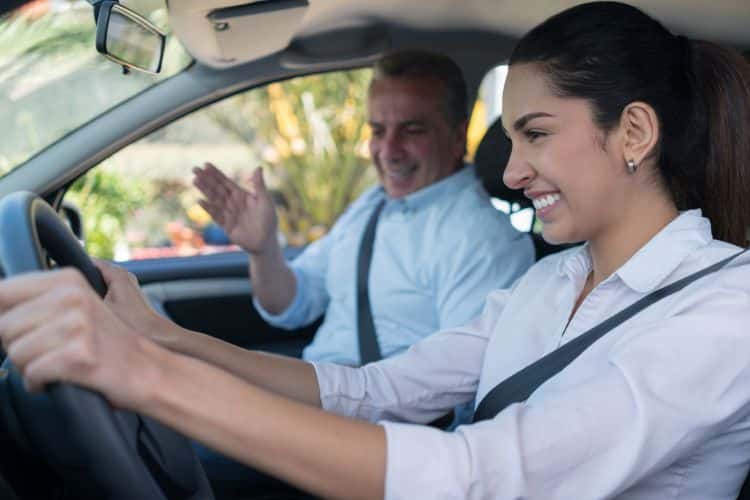 A driver and a instructor chatting inside a vehicle during a driving lesson.